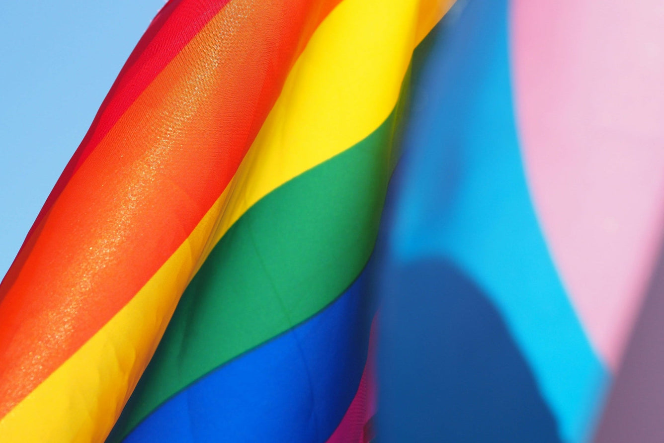Close-up of a rainbow flag with a blue sky background.